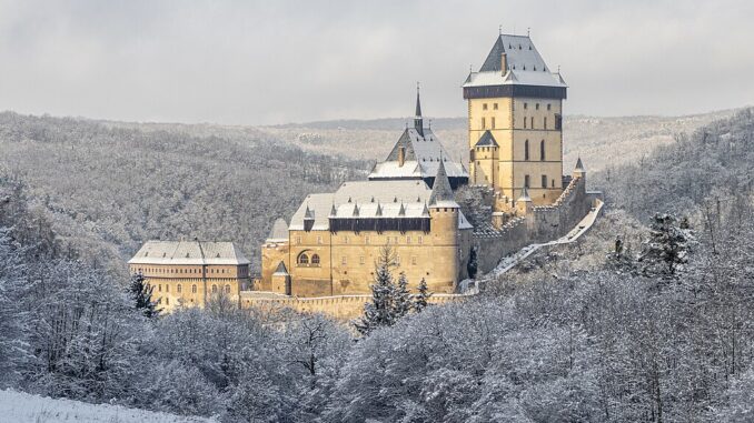 Zimní pohled na Karlštejn od jihovýchodu ze sedla mezi Plešivcem a Haknovou. Zdroj: Wikipedie, CC BY-SA 4.0. Autor: Radomír Šalda
